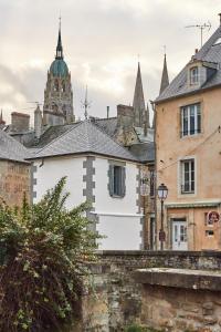 un edificio blanco con una torre de reloj en una ciudad en La Plus Petite Maison De France, en Bayeux