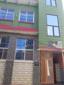 GovardhanRADHA APARTMENTS Stay的一座带前门和窗户的绿色房子