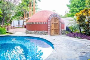 ein Kuppelhaus mit einer Holztür neben einem Swimmingpool in der Unterkunft El Molino Hotel Boutique in Río Verde
