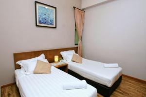 twee bedden in een hotelkamer met witte lakens bij The Retreat Mountain & Sunrise view Hilltop Hotel Apartment in Cameron Highlands in Cameron Highlands