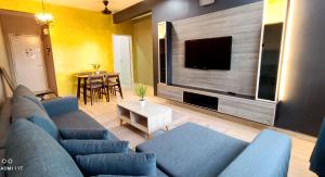 a living room with a blue couch and a flat screen tv at Homestay Kuala Terengganu Baroqah Homestay in Kuala Terengganu