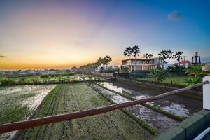 a view of a field from a fence with the sunset at Villa Flambard in Canggu