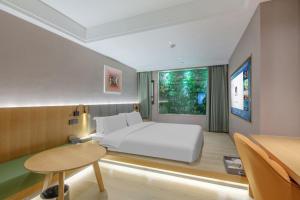 una camera da letto con un grande letto bianco e un tavolo di Shijiazhuang Changan Wanda Plaza Jianhua City Plaza Qiuguo Hotel a Shijiazhuang