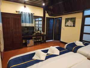 two beds in a room with a desk and a television at Villa Le Tam Tam Boutique Hotel in Luang Prabang +42 photos