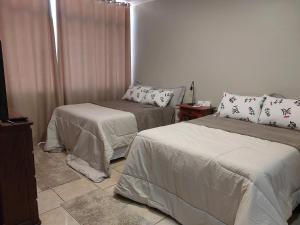 a room with two beds and a television in it at Casa da Vó Cida in Espirito Santo Do Pinhal