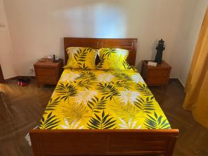 a bedroom with a bed with a yellow blanket with palm leaves at Appartement T4 Standing Diégo-Suarez in Antsiranana