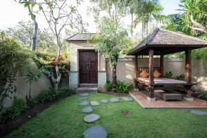 a gazebo with a bench in a garden at Aldeoz Grand Kancana Villas Resort Bali in Kerobokan