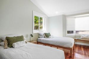 a white room with two beds and a window at Ocean Front Luxury The Lambeth Walk in Bundeena
