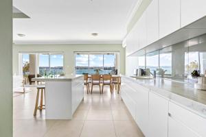 a kitchen with white cabinets and a table with chairs at Ocean Front Luxury The Lambeth Walk in Bundeena