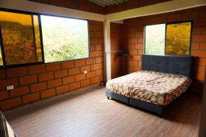 a bedroom with a bed in a room with two windows at Retro Finca Urrao - Peaceful Avocado Farm Retreat in Urrao