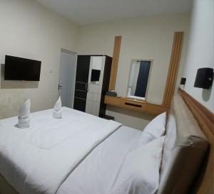 a bedroom with a white bed and a television at NiEr Guesthouse Zwei in Lumajang