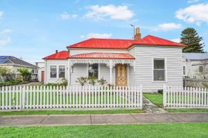 Biały dom z czerwonym dachem i białym płotem w obiekcie Hewlett Cottage w mieście Port Fairy