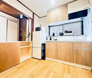 a kitchen with a white refrigerator and wooden cabinets at Mulan Stay 嵯峨嵐山 in Shimo saga