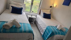 two twin beds in a room with a window at Chakas Rock Chalet 39 in Ballito +24 photos