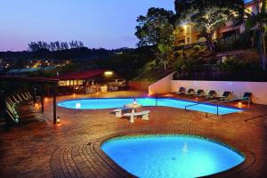 a large pool with a table and chairs next to a building at Chakas Rock Chalet 39 in Ballito