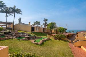 a house with a yard with a putting green at Chakas Rock Chalet 39 in Ballito