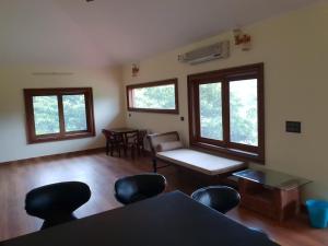 a living room with a table and chairs and windows at Tropical Blooms by StayApart in Kutta