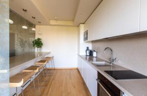 a kitchen with a row of stools and a counter at DRUSKININKŲ PANORAMA Apartamentai in Druskininkai