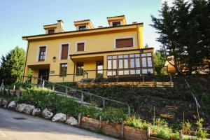 a yellow house sitting on top of a hill at Hotel Rural Valle de Cuaña in Santibáñez de Murias