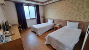 a hotel room with two beds and a window at Hotel Parkwood Incheon Airport in Incheon