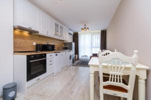 eine Küche mit weißen Schränken und einem Tisch und Stühlen in der Unterkunft LDV 13 1-Bedroom Apartments Free private parking in Plowdiw