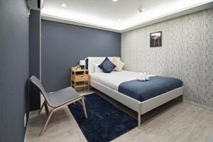 um pequeno quarto com uma cama e uma cadeira em 旅タイム・時光　鶴橋駅 em Osaka