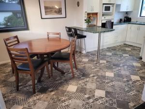 a kitchen with a wooden table and chairs in a kitchen at Esplanade Townhouse in Gisborne