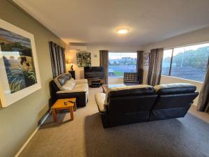 a living room with a black leather couch and chair at Esplanade Townhouse in Gisborne