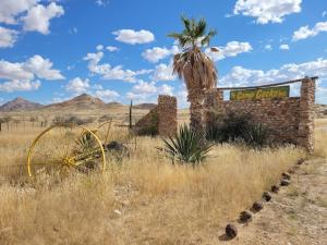 an old brick building with a palm tree and a sign at Camp Gecko - PRIVATE NATURE RESERVE; TENTED CAMP AND CAMPSITE in Solitaire