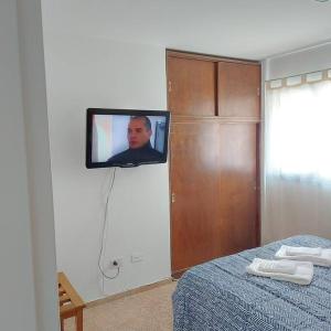 einen TV, der an einer Wand neben einem Bett hängt in der Unterkunft Microcentro de la Docta in Cordoba