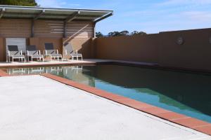 Una piscina con sillas al lado de un edificio. en Adina Vineyard, en Lovedale