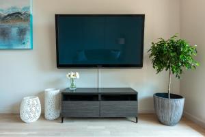 a flat screen tv on a wall with two plants at Sun-Drenched Sophistication in Victoria