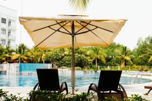 two chairs and an umbrella in front of a swimming pool at Happy House in Ho Chi Minh City