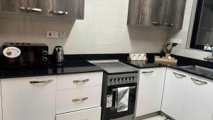 a kitchen with white cabinets and a black stove top oven at imora homes 5 minutes fromJomo Kenyatta international airport in Syokimau