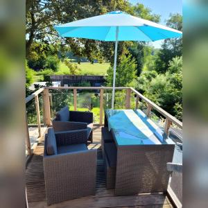 a deck with a table and chairs and an umbrella at Ferienwohnung am Töschenbach in Hennstedt
