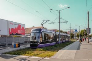 a purple train on the tracks next to a street at Perfect, relaxing and cozy apartment in Timişoara