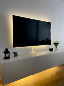 TV de pantalla plana en un centro de entretenimiento blanco en Lucus Urban Centre, en Lugo
