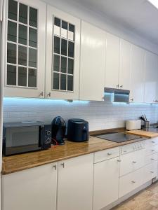 a kitchen with white cabinets and a microwave at Lucus Urban Centre in Lugo +13 photos