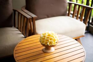 un vase de fleurs jaunes assis sur une table en bois dans l'établissement Bali Niksoma Boutique Beach Resort, à Legian