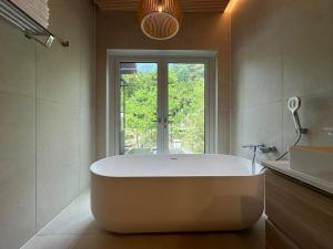 a large white tub in a bathroom with a window at Gangchon 1225 Pension in Chuncheon