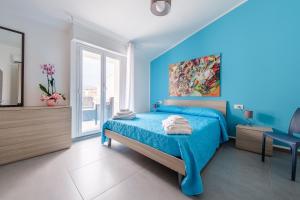 a blue bedroom with a bed and a window at Alba's Home Casa Vacanze in Valdina