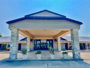 Un edificio con un pabellón con plantas en macetas en el frente. en Owensville Inn, en Owensville