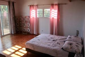 a bedroom with a bed and a window with red curtains at La Kaz Filaos in Saint-Paul