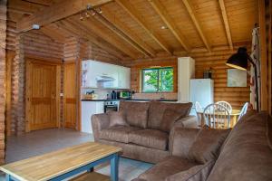 a living room with a couch and a kitchen at Quail Lodge - Nordic Log Cabin in Selby