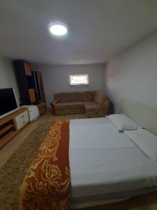 a bedroom with a large bed and a couch at Nova Kuća na idiličnoj lokaciji sa mogućnosti korištenja pečenjare nije namijenjena malodobnoj djeci i osobama koje su osjetljive na miris dima in Šćapovec