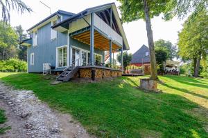 a blue house with a porch on a lawn at Namelis ant ežero kranto "Mėlynas namelis" in Tytuvėnai +49 photos
