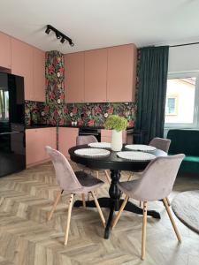 une cuisine avec des placards roses, une table et des chaises dans l'établissement ColourApartament, à Oława