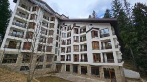 a tall white building with a tree in front of it at ICEBERG Ski Apartment No19 in Pamporovo