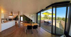 a kitchen and living room with a dining table and a patio at La Maison du Sabotier in Custinne