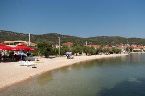 a beach with umbrellas and people on the sand and water at Guest House Dobriša in Vinišće
